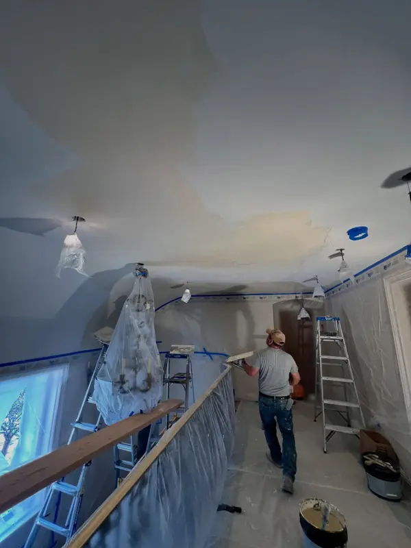 Plasterer applying Venetian plaster to a hallway ceiling with chandeliers and floors protected, The Avenues, Salt Lake City, Utah