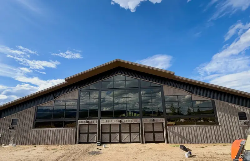 Restained board-and-batten siding and gabled window wall on the main elevation of the equestrian facility at Promontory, Park City, Utah – exterior wood restoration