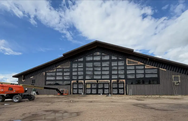 Boom lift at the gabled main elevation of the equestrian facility at Promontory, Park City, Utah during exterior restoration