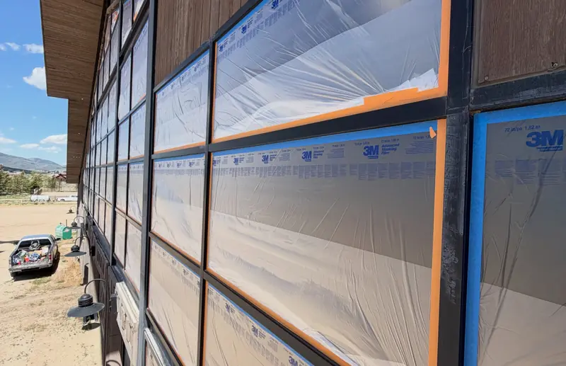 Window wall masked with protective film before refinishing, equestrian facility at Promontory, Park City, Utah – exterior restoration in progress